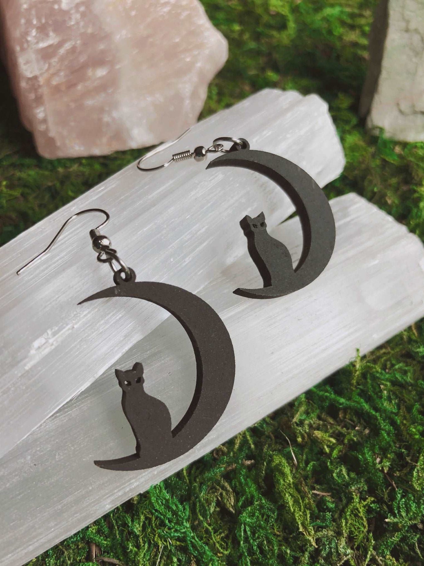 Pictured is a pair of earrings featuring a black cat sitting on a black crescent moon. They are made of wood.  Black Cat and Moon Earrings 