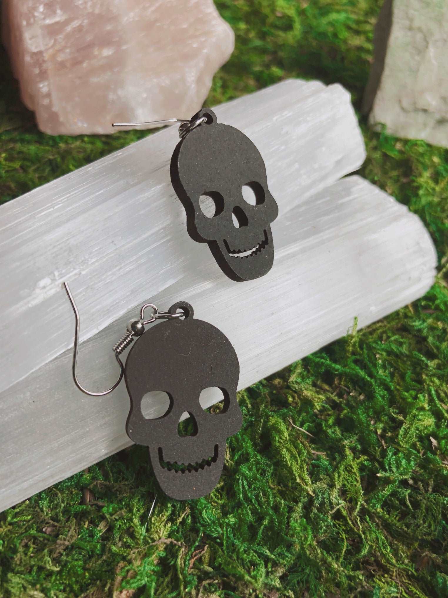 Pictured is a pair of black earrings featuring a skull. They are made of wood. Black Skull Earrings