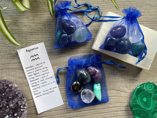 An image of a collection of tumbled stones in an organza bag. To the side is a piece of paper that describes what each tumbled stone's metaphysical properties are. AQUARIUS Zodiac Tumbled Crystal Bag 