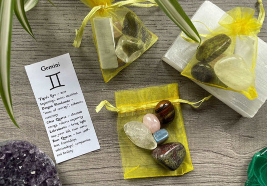 An image of a collection of tumbled stones in an organza bag. To the side is a piece of paper that describes what each tumbled stone's metaphysical properties are. GEMINI Zodiac Tumbled Crystal Bag