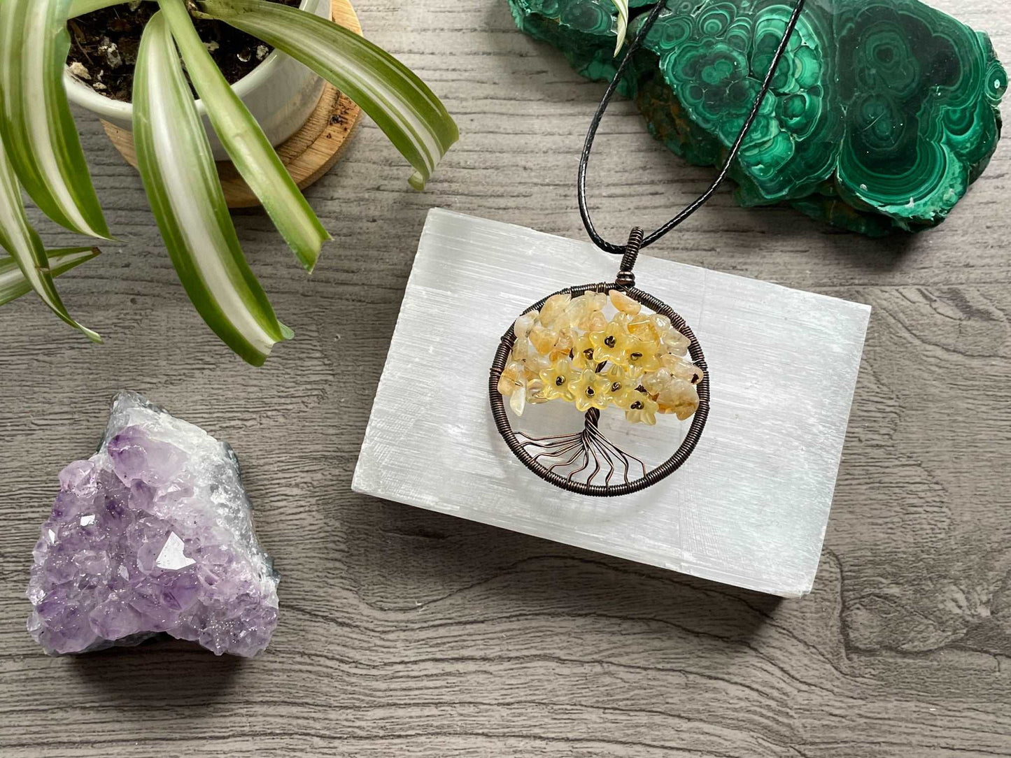 An image of a necklace featuring a wire-wrapped pendant. The wire is in the shape of a tree and the leaves on the tree are polished chips of citrine. Citrine Crystal Wire-Wrapped Tree Of Life Necklace close up