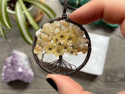 An image of a necklace featuring a wire-wrapped pendant. The wire is in the shape of a tree and the leaves on the tree are polished chips of citrine. Citrine Crystal Wire-Wrapped Tree Of Life Necklace