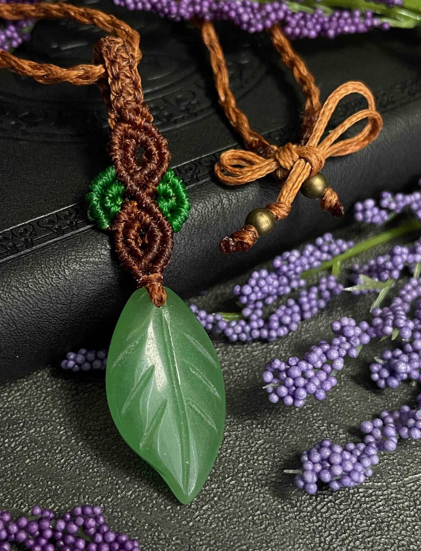 Pictured is a green aventurine cabochon wrapped in macrame thread. A gothic book and flowers are nearby. Green Aventurine Leaf Macramé Necklace (Twisted Nightshade Jewellery) - The Wandering Fox Emporium, Your Crystal Store clasp