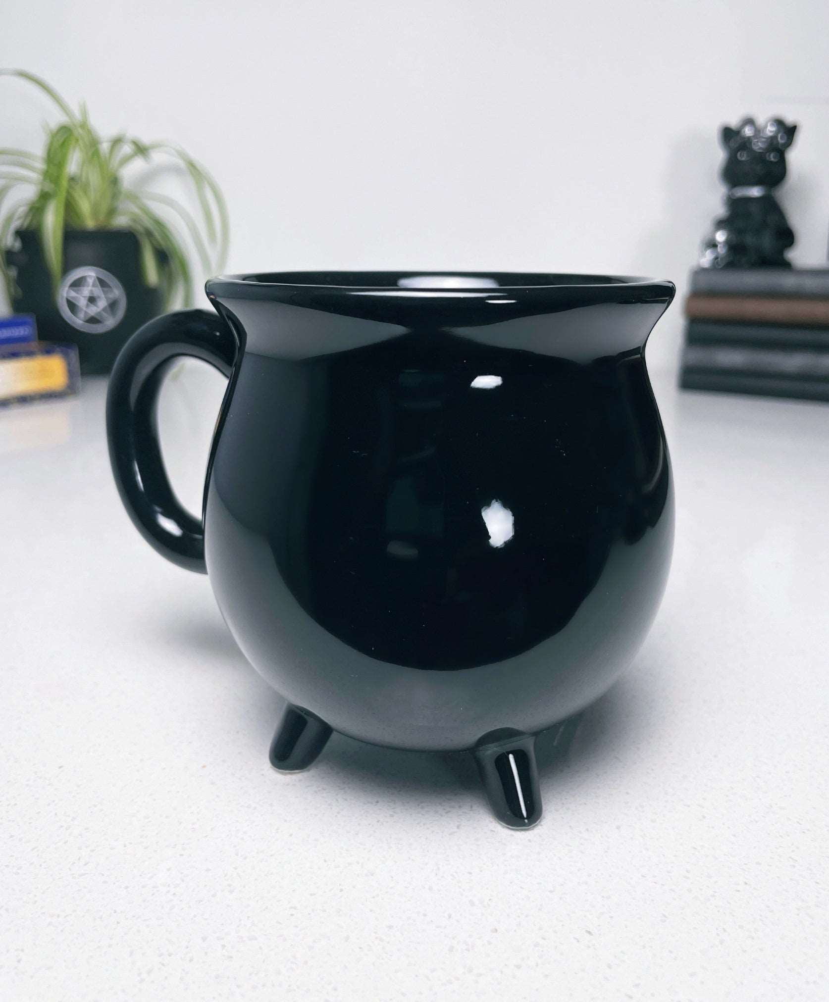 Pictured is a black ceramic mug in the shape of a cauldron.