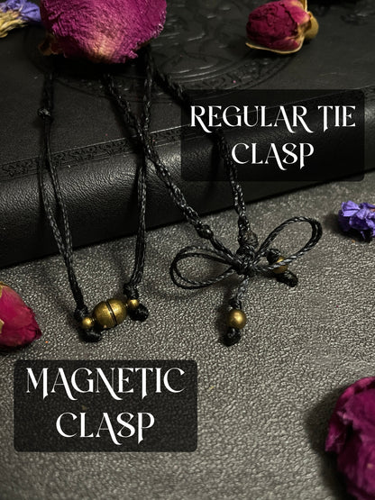 Pictured is a marcasite in agate cabochon wrapped in macrame thread. A gothic book and flowers are nearby. Marcasite in Agate Macramé Necklace (Twisted Nightshade Jewellery) - The Wandering Fox Emporium, Your Crystal Store clasp option