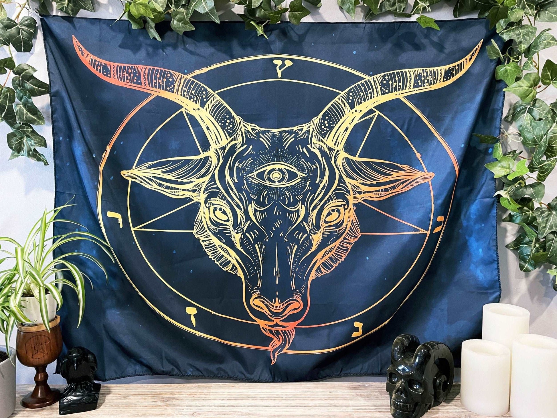 Pictured is a large wall tapestry with a dark blue background and an image of baphomet printed in yellow and orange. Baphomet Wall Tapestry