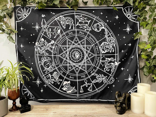 Pictured is a large wall tapestry with a black background and a large zodiac wheel printed in white on it. Astrology Wheel Wall Tapestry