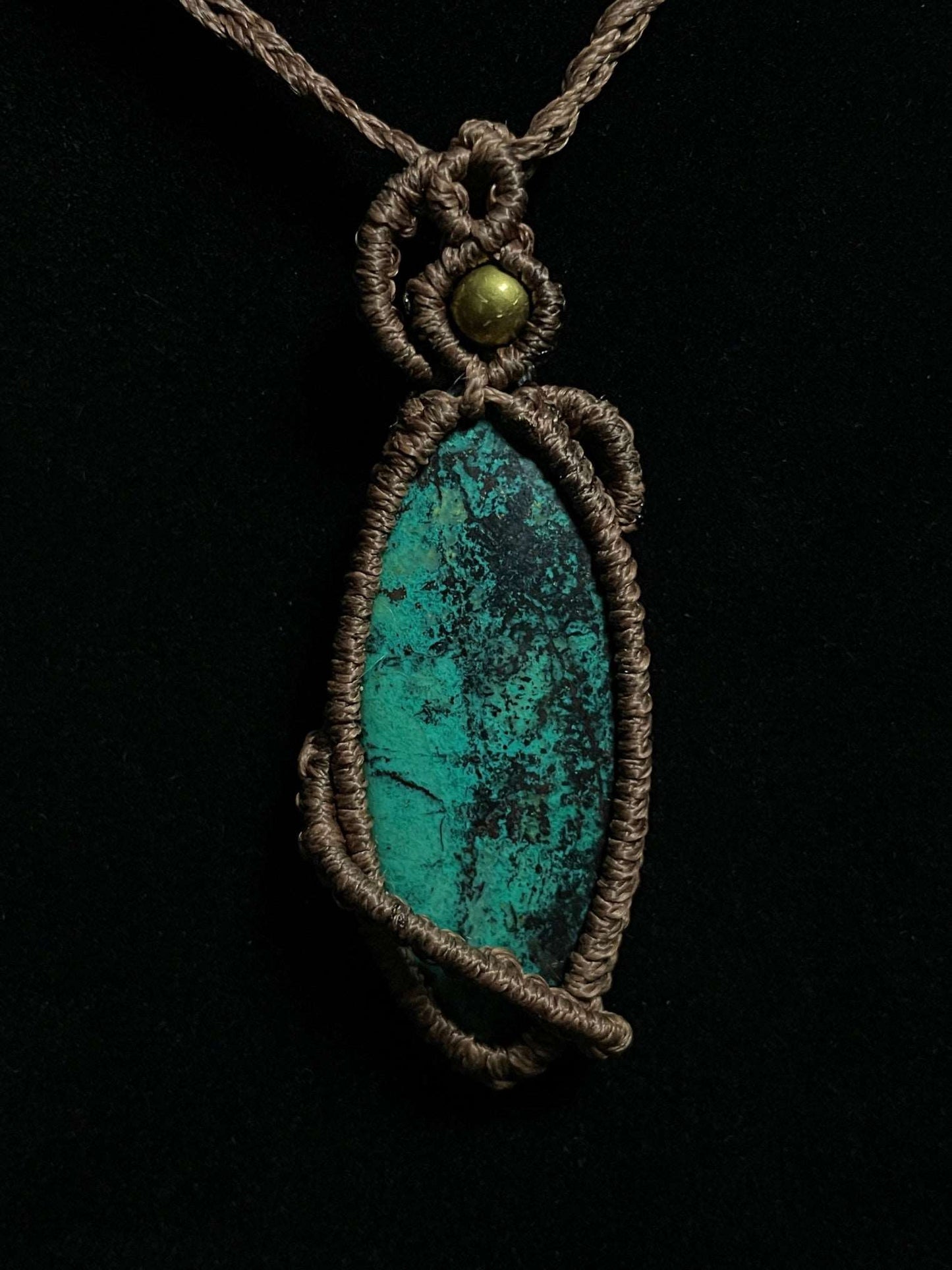 Pictured is a chrysocolla cabochon wrapped in macrame thread. A gothic book and flowers are nearby. Chrysocolla Macramé Necklace (Twisted Nightshade Jewellery) - The Wandering Fox Emporium, Your Crystal Store black