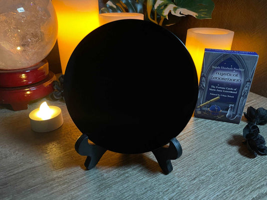 Pictured is a scrying mirror on a stand. The scrying mirror is carved out of black obsidian.Black Obsidian Scrying Mirror 12cm