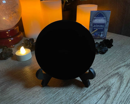 Pictured is a scrying mirror on a stand. The scrying mirror is carved out of black obsidian. Black Obsidian Scrying Mirror 10cm front