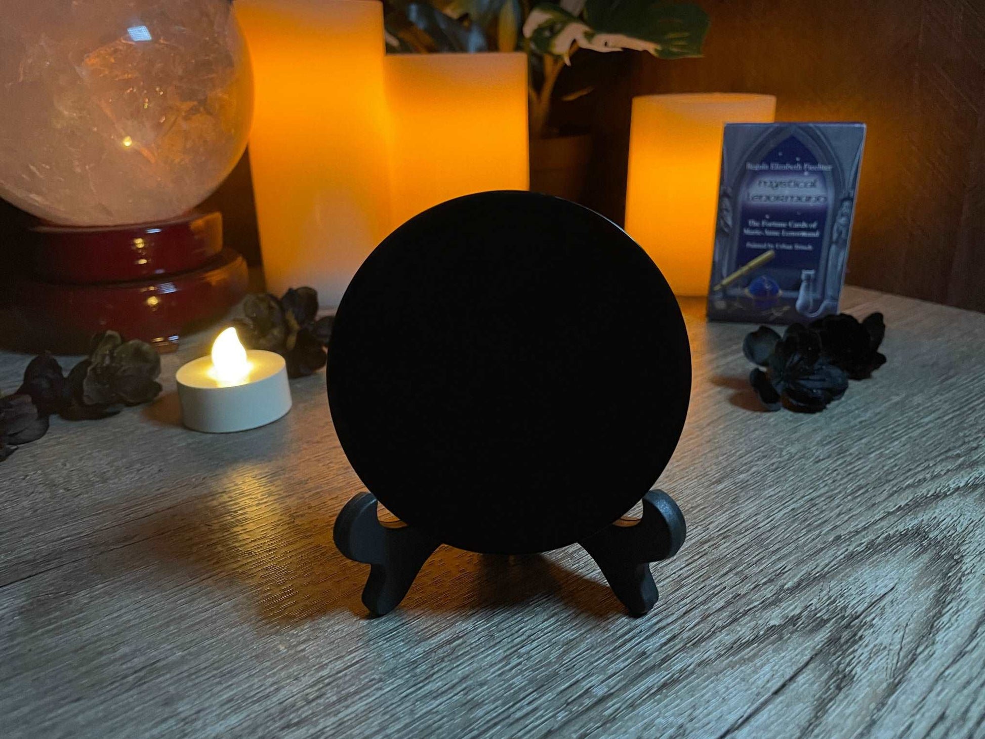 Pictured is a scrying mirror on a stand. The scrying mirror is carved out of black obsidian. Black Obsidian Scrying Mirror 8cm front