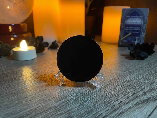 Pictured is a scrying mirror on a stand. The scrying mirror is carved out of black obsidian. Black Obsidian Scrying Mirror 5cm (with stand) 