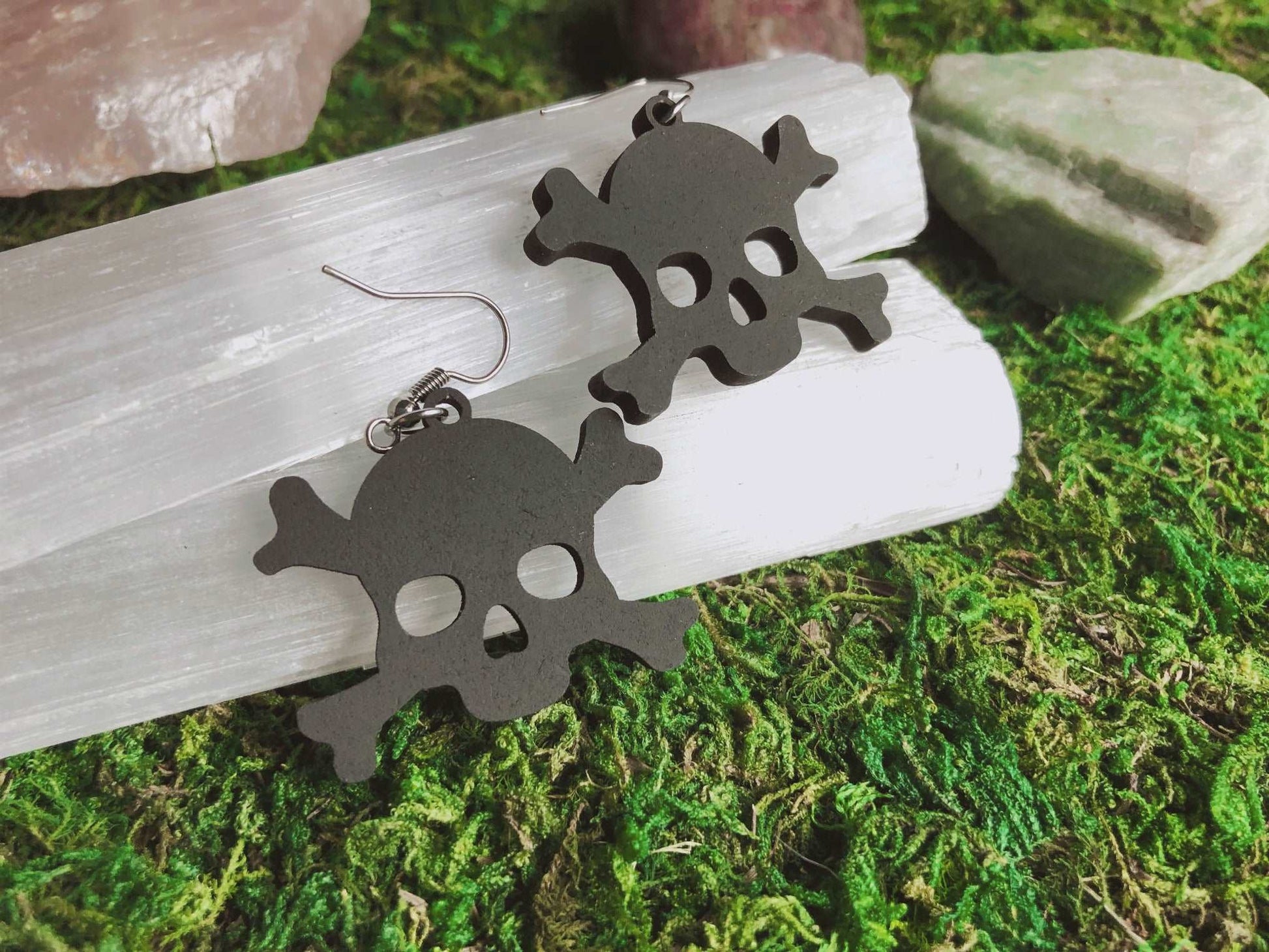 Pictured is a pair of earrings featuring a black skull and crossbone. They are made of wood.  Black Skull and Crossbone Earrings