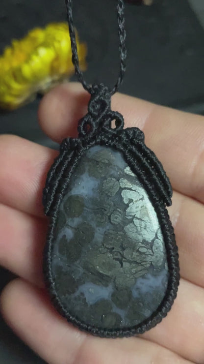 Pictured is a marcasite in agate cabochon wrapped in macrame thread. A gothic book and flowers are nearby. Marcasite in Agate Macramé Necklace (Twisted Nightshade Jewellery) - The Wandering Fox Emporium, Your Crystal Store video