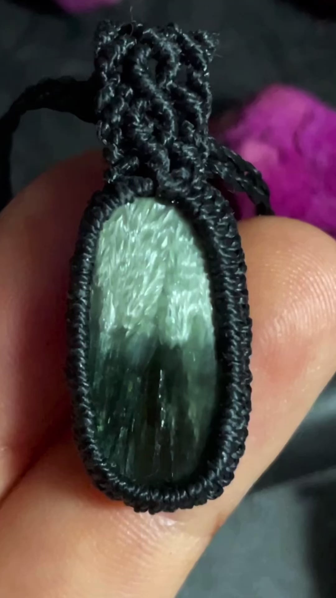 Pictured is a seraphinite cabochon wrapped in macrame thread. A gothic book and flowers are nearby. Seraphinite Macramé Necklace (Twisted Nightshade Jewellery) - The Wandering Fox Emporium, Your Crystal Store video