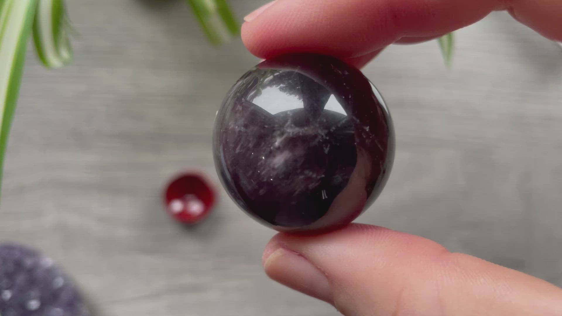 A polished sphere of amethyst is shown in the image. The crystal is a purple color and has a smooth, shiny surface. Amethyst Crystal Sphere 31mm (B) video