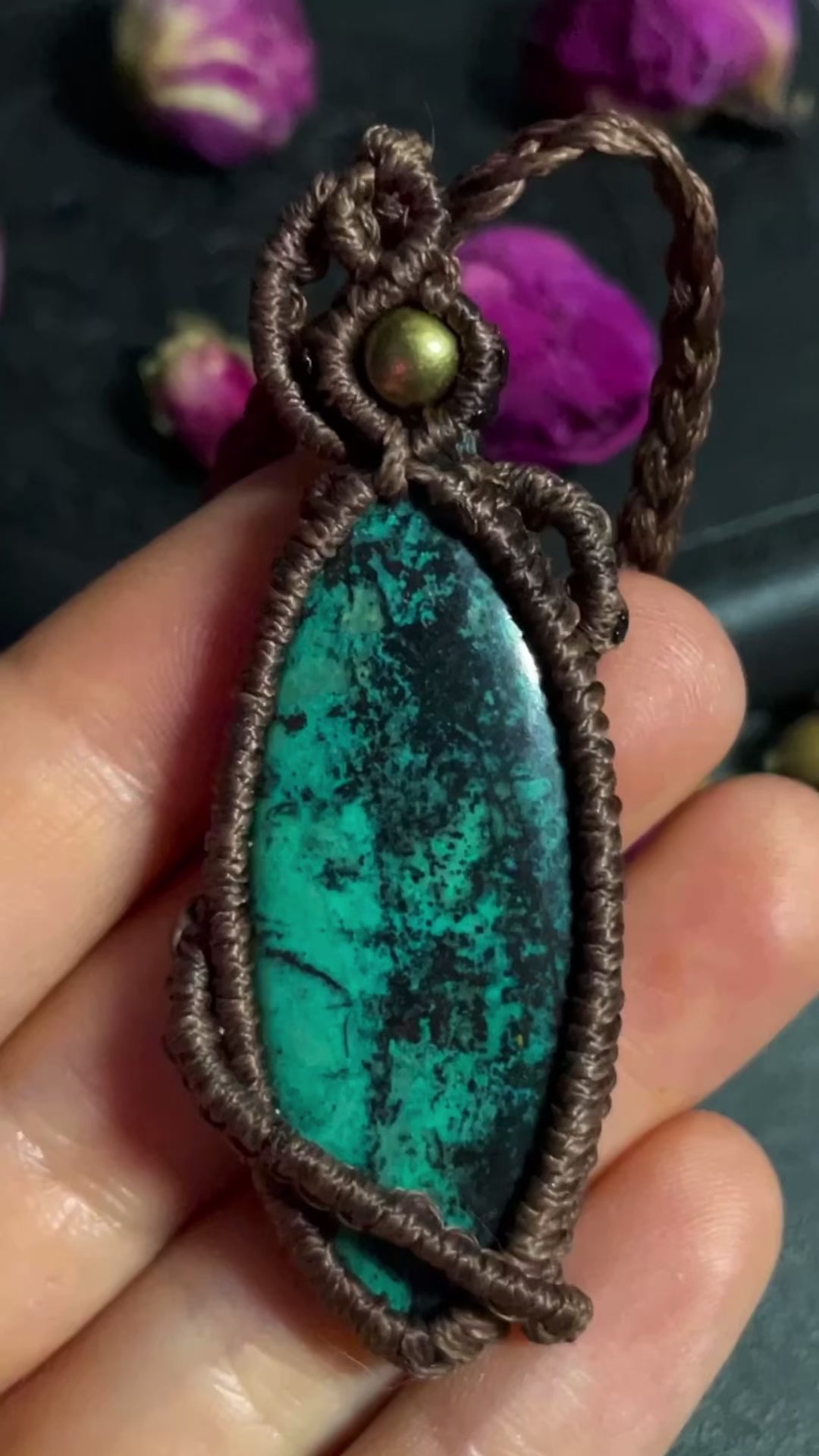 Pictured is a chrysocolla cabochon wrapped in macrame thread. A gothic book and flowers are nearby. Chrysocolla Macramé Necklace (Twisted Nightshade Jewellery) - The Wandering Fox Emporium, Your Crystal Store video