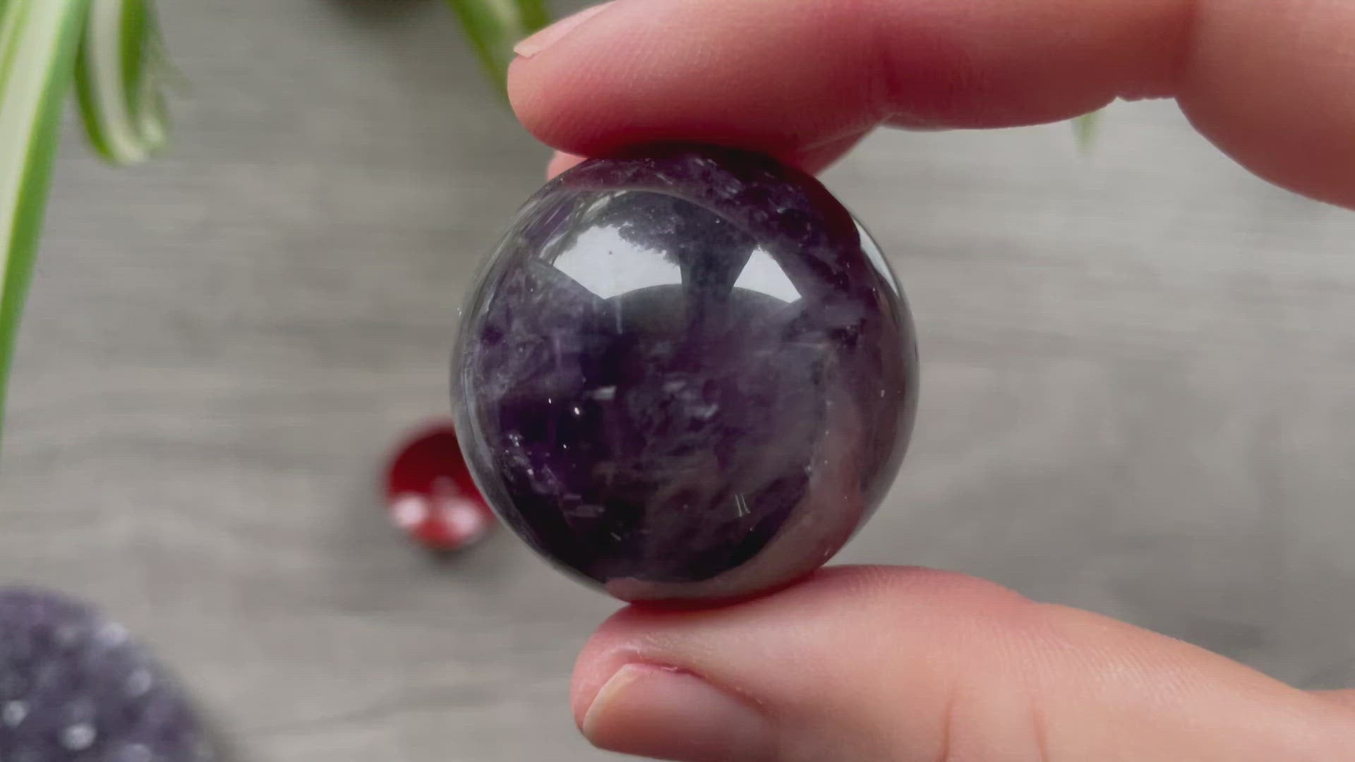 A polished sphere of amethyst is shown in the image. The crystal is a purple color and has a smooth, shiny surface. Amethyst Crystal Sphere 33mm video