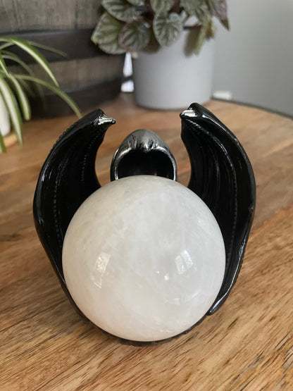 Pictured is a sphere stand in the shape of a hooded figure with dragon wings. Masked Dragon Crystal Sphere Stand  example