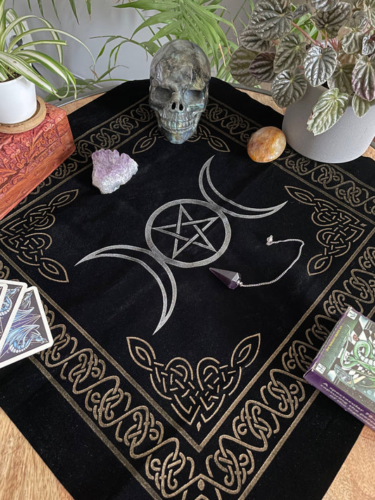 Pictured is a black velvet altar cloth with a silver pentacle and triple moon symbol in the middle. Triple Moon Altar Cloth