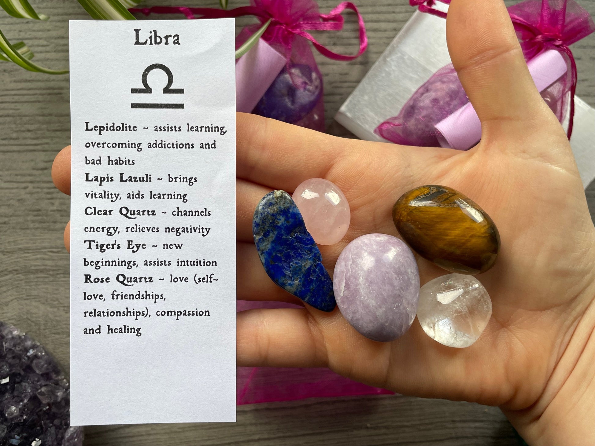 An image of a collection of tumbled stones in an organza bag. To the side is a piece of paper that describes what each tumbled stone's metaphysical properties are. LIBRA Zodiac Tumbled Crystal Bag crystals