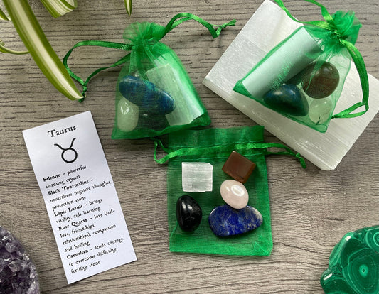 An image of a collection of tumbled stones in an organza bag. To the side is a piece of paper that describes what each tumbled stone's metaphysical properties are. TAURUS Zodiac Tumbled Crystal Bag 