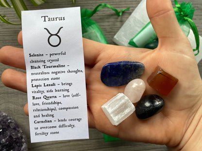 An image of a collection of tumbled stones in an organza bag. To the side is a piece of paper that describes what each tumbled stone's metaphysical properties are. TAURUS Zodiac Tumbled Crystal Bag crystals