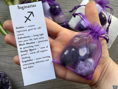 An image of a collection of tumbled stones in an organza bag. To the side is a piece of paper that describes what each tumbled stone's metaphysical properties are. SAGITTARIUS Zodiac Tumbled Crystal Bag front