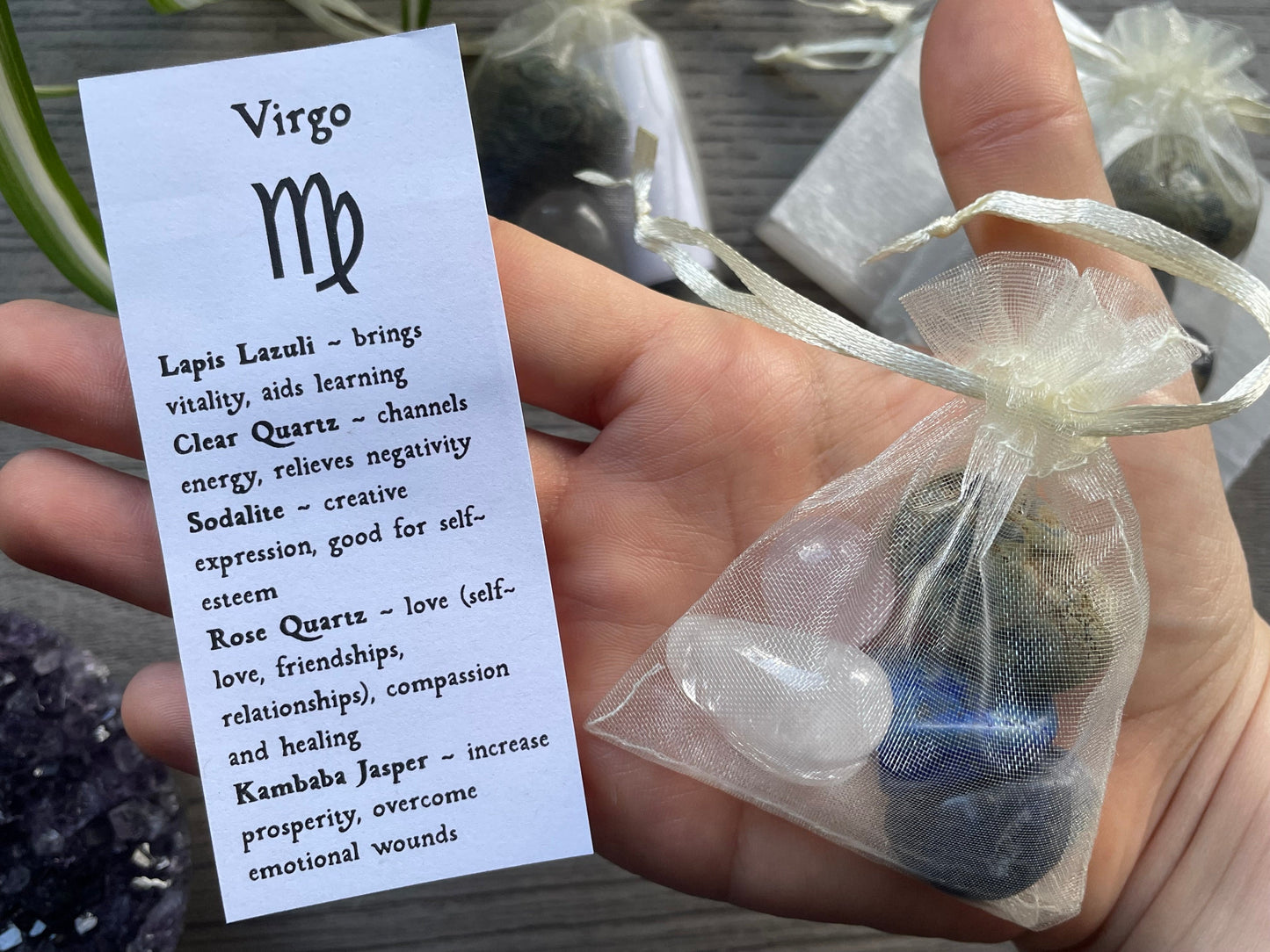 An image of a collection of tumbled stones in an organza bag. To the side is a piece of paper that describes what each tumbled stone's metaphysical properties are. VIRGO Zodiac Tumbled Crystal Bag close up