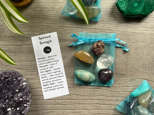 An image of a collection of tumbled stones in an organza bag. To the side is a piece of paper that describes what each tumbled stone's metaphysical properties are. SPIRITUAL STRENGTH Tumbled Crystal Bag