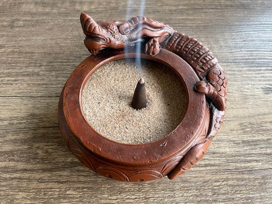 Pictured is a brown incense sand holder in the shape of a bowl with a dragon laying on the side of the bowl. Dragon Ceramic Incense Bowl with Sand 