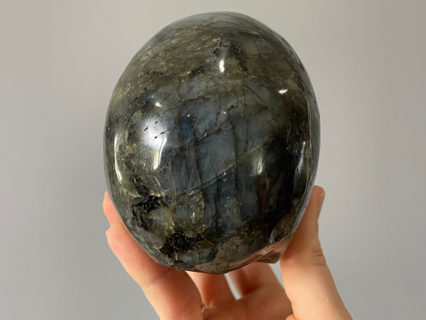 Pictured is a large skull carved out of labradorite with blue and green and yellow flashes. Labradorite Crystal Skull (1.3kg) - The Wandering Fox Emporium, Your Metaphysical Store back