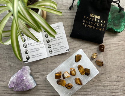 Pictured is a rune set made of tiger's eye tumbled stones. A black velvet bag and instructions sit nearby, Tiger's Eye Mini Rune Set (24 runes) close up