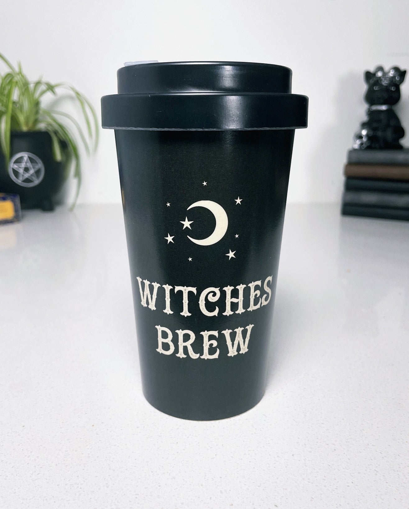 A black eco travel mug with a white words that say "Witches Brew" on the side. "Witches Brew" Eco Travel Mug front