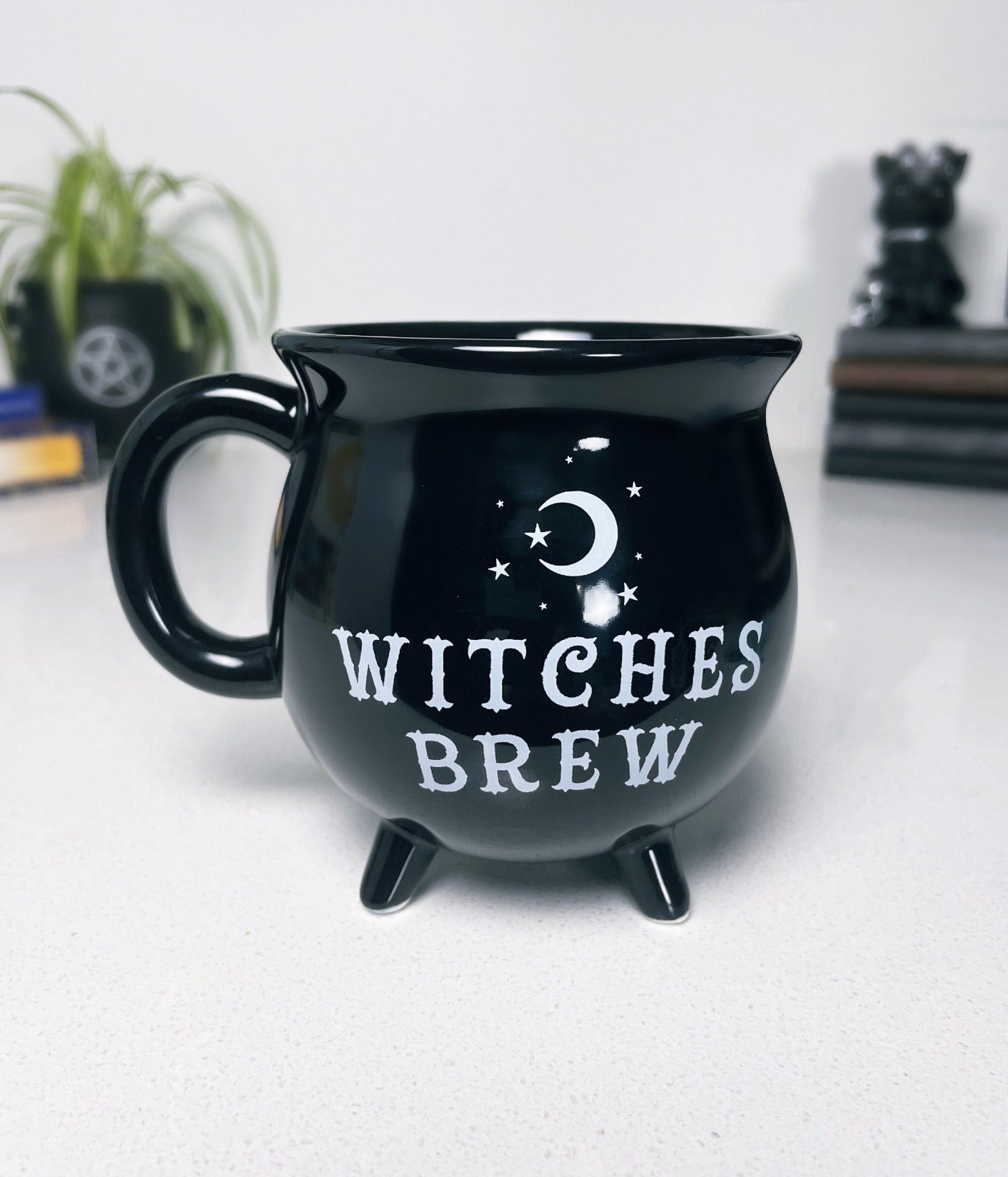 A black ceramic cauldron-shaped mug with a white label that says "Witches Brew" on the side.  "Witches Brew" Cauldron Ceramic Mug