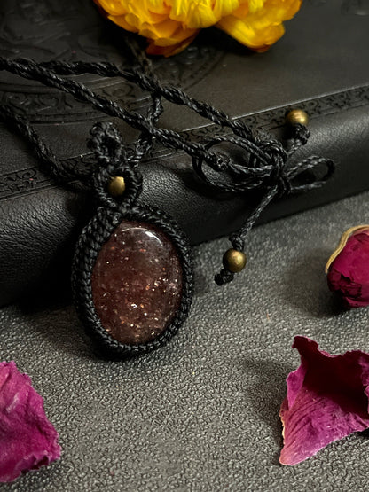 Pictured is a strawberry quartz cabochon wrapped in macrame thread. A gothic book and flowers are nearby. Strawberry Quartz Macramé Necklace (Twisted Nightshade Jewellery) - The Wandering Fox Emporium, Your Crystal Store clasp