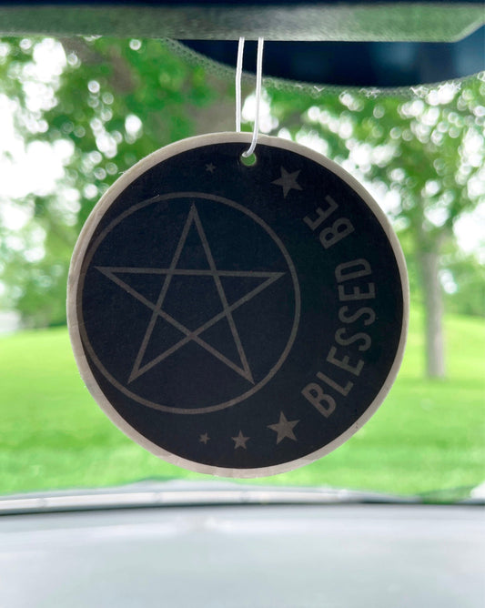 An image of a circular car air freshener featuring a pentagram and a crescent moon on a black background. The words "Blessed Be" are written in white, cursive letters at the bottom of the air freshener. "Blessed Be" Air Freshener (Vanilla Scent)