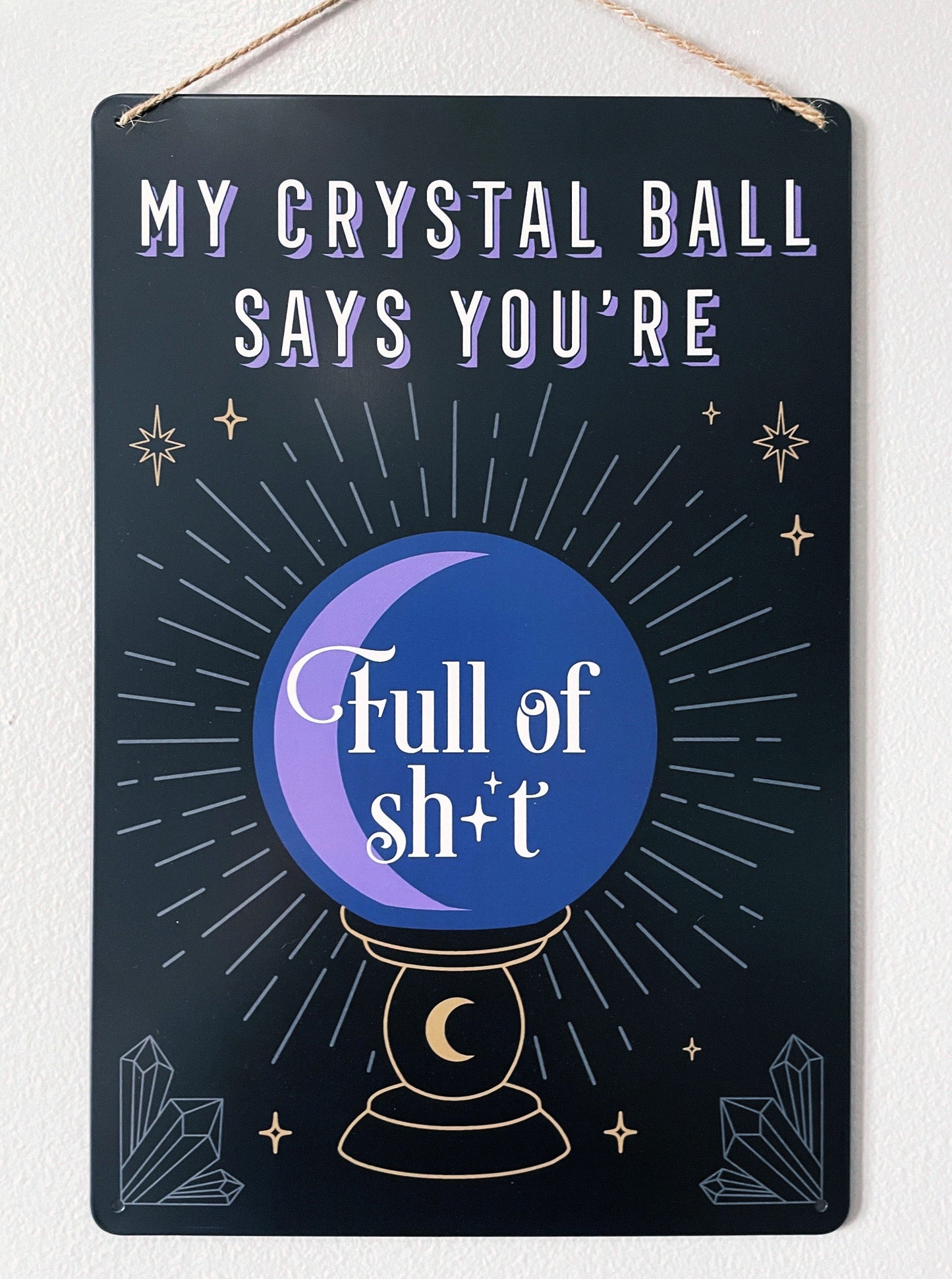 An image of a metal wall sign featuring a crystal ball design with the phrase "My crystal ball says you're full of shit" written in bold letters. The crystal ball design is illustrated in white against a deep purple background, with intricate lines and details that create a mystical and magical look. "My Crystal Ball Says You're Full of Shit" Metal Sign front