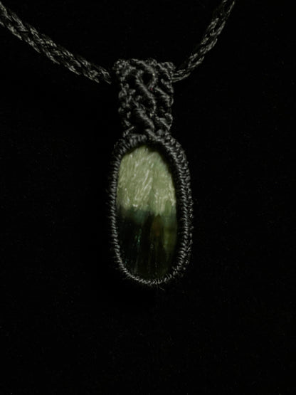 Pictured is a seraphinite cabochon wrapped in macrame thread. A gothic book and flowers are nearby. Seraphinite Macramé Necklace (Twisted Nightshade Jewellery) - The Wandering Fox Emporium, Your Crystal Store black