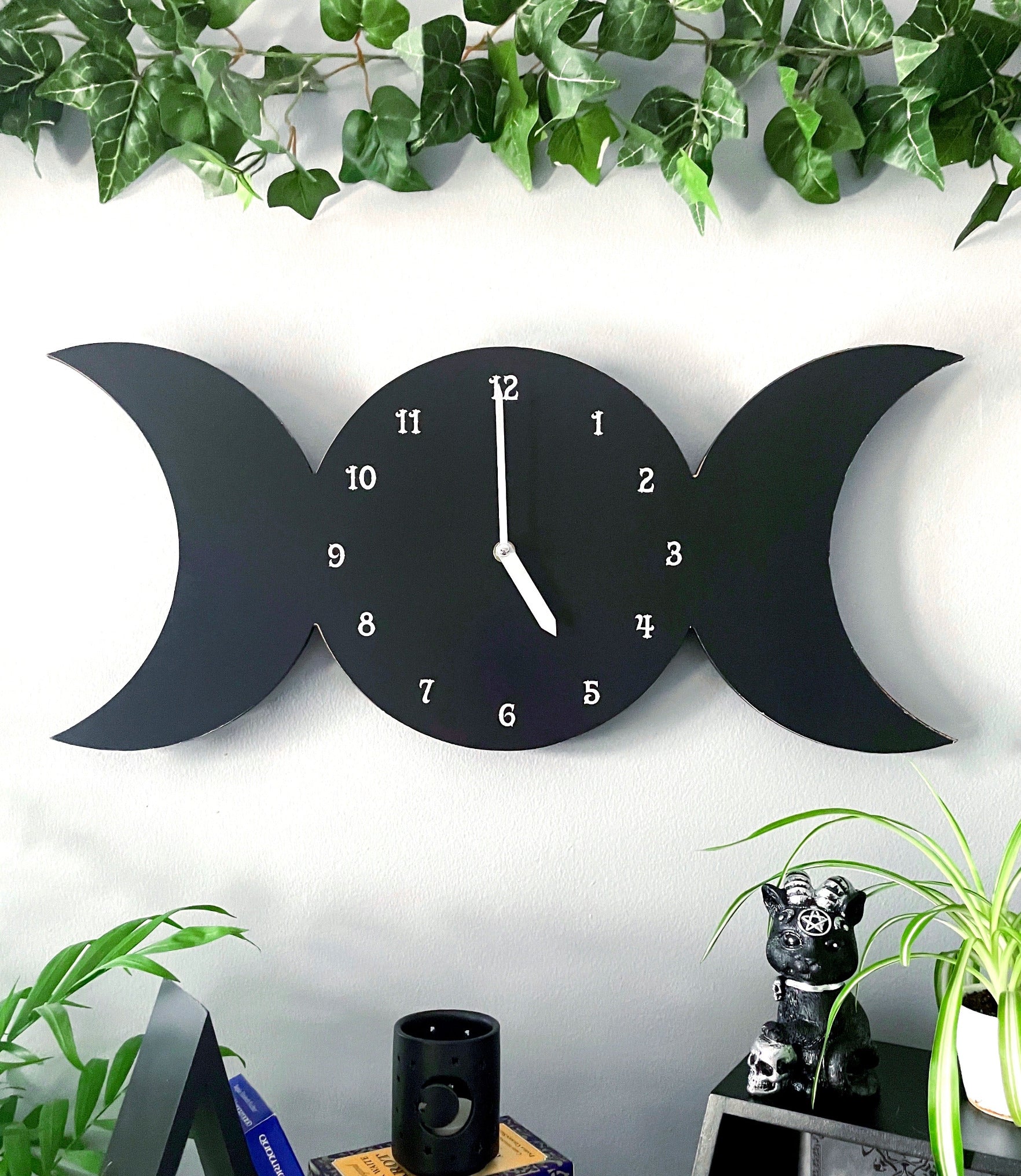 Pictured is a wall clock in the shape of a triple moon with the moon phases on it. Triple Moon Wall Clock