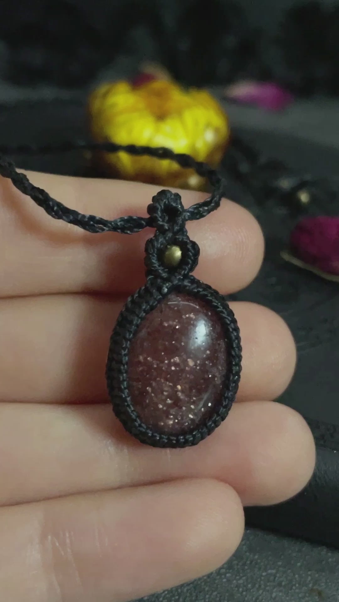 Pictured is a strawberry quartz cabochon wrapped in macrame thread. A gothic book and flowers are nearby. Strawberry Quartz Macramé Necklace (Twisted Nightshade Jewellery) - The Wandering Fox Emporium, Your Crystal Store video