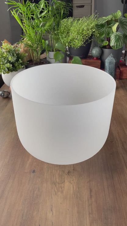  A photo of a quartz crystal singing bowl and a mallet on a wooden surface. The crystal singing bowl is made of clear quartz and has a smooth, round shape. video