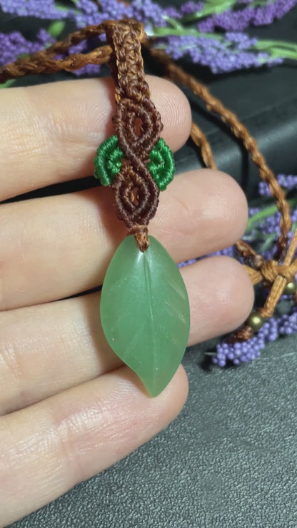 Pictured is a green aventurine cabochon wrapped in macrame thread. A gothic book and flowers are nearby. Green Aventurine Leaf Macramé Necklace (Twisted Nightshade Jewellery) - The Wandering Fox Emporium, Your Crystal Store video